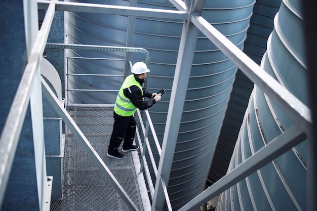 factory-silos-worker-standing-metal-platform-industrial-storage-tanks-looking-tablet-about-food-production_342744-440 factory-silos-worker-standing-metal-platform-industrial-storage-tanks-looking-tablet-about-food-production_342744-440